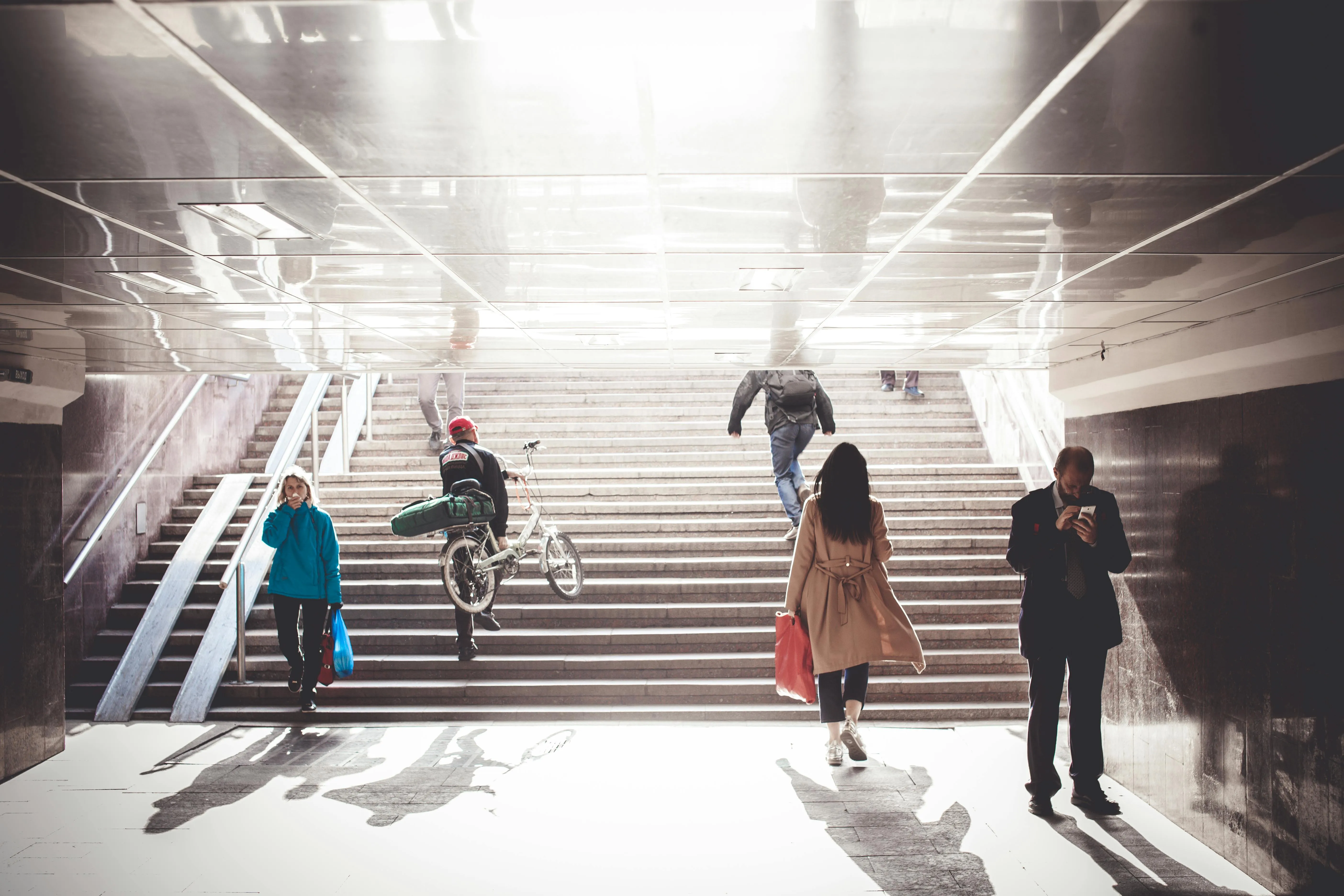 image of underground stairs going up the daylight with people living their daily lives