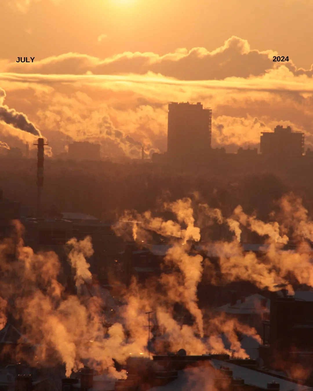 image of factory chimney with clouds of smoke with yellow sunset tint